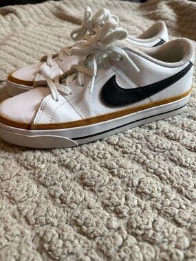 Nike women’s White Sneakers with Black Swoosh and Gold Accent